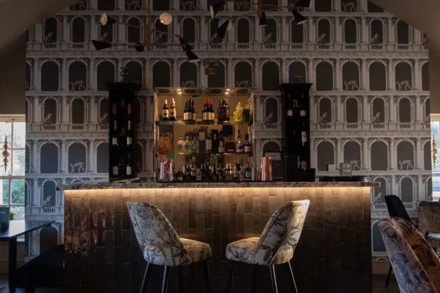 The events room bar, with shelves of bottles against the arched wallpaper