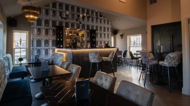 Dark tables and upholstered chairs set out in the events room